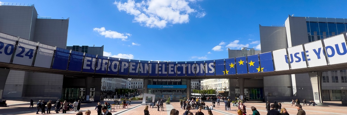 La gente camina hacia una pancarta que promociona las elecciones europeas frente al Parlamento Europeo en Bruselas, Bélgica, el 10 de abril de 2024.