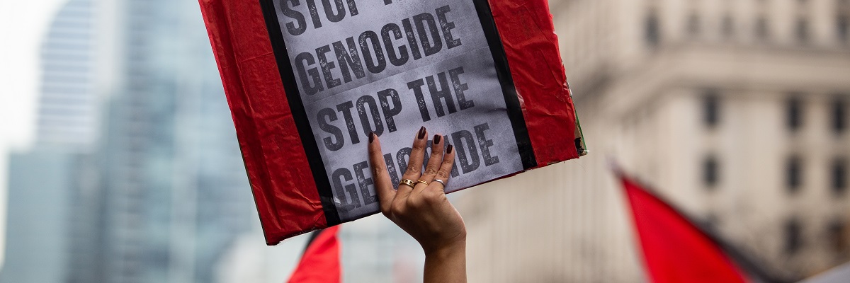 Eine Person hält bei einer palästinensischen Demonstration in Toronto, Kanada, gegen den Krieg in Gaza ein Schild mit der Aufschrift „Stoppt den Völkermord“ hoch