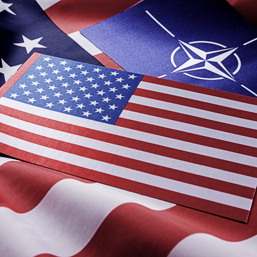 NATO symbol on the background of the American flag. Organization of the North Atlantic Treaty.