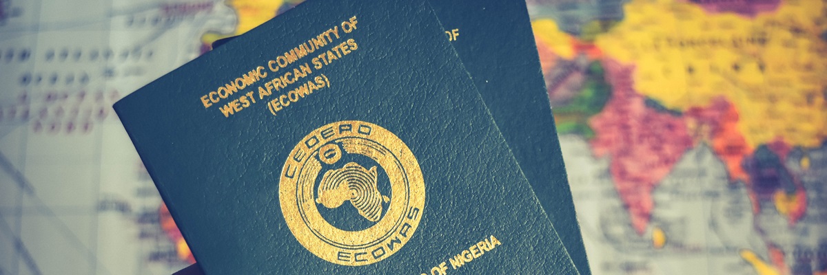 Ecowas passport in African hand, African holding two Green Nigerian Passports with map in the background