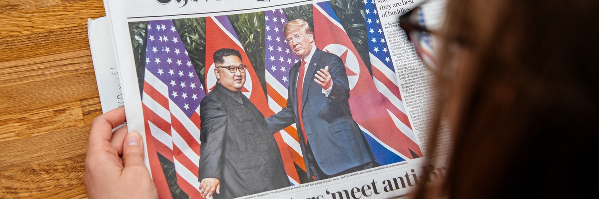 PARIS, FRANCE - JUNE 13, 2018: Woman reading The Daily Telegrpah newspaper in the office showing on cover U.S. President Donald Trump meeting North Korean leader Kim Jong-un in Singapore