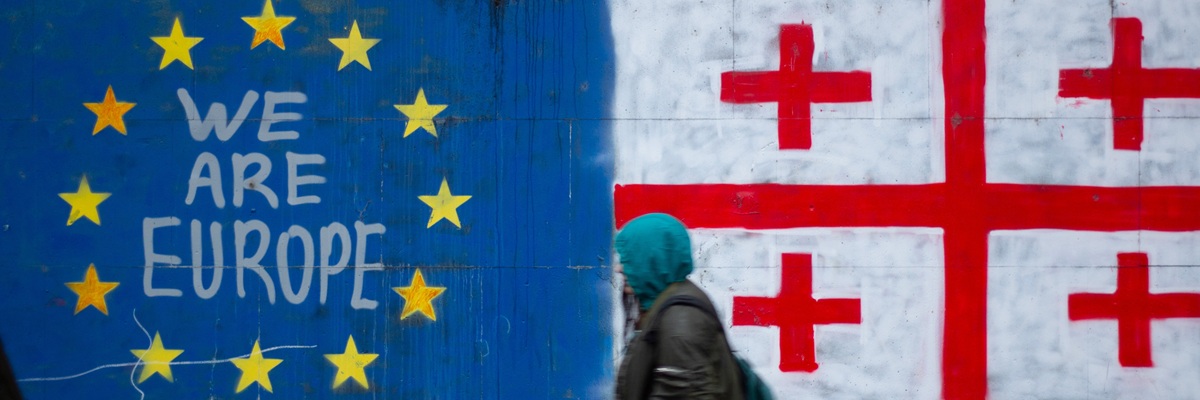 Tbilissi, Géorgie - 25 novembre 2024 : Les gens sont flous près du texte Nous sommes le drapeau de l'Europe, de l'UE et de la Géorgie, une croix, une étoile jaune sur le mur bleu de la maison. Manifestation pacifique contre le résultat des élections légis