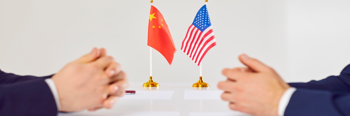 Flags of America and China atand on table during talks between diplomats and businessmen. American and Chinese representatives sit opposite each other to discuss relations between countries.