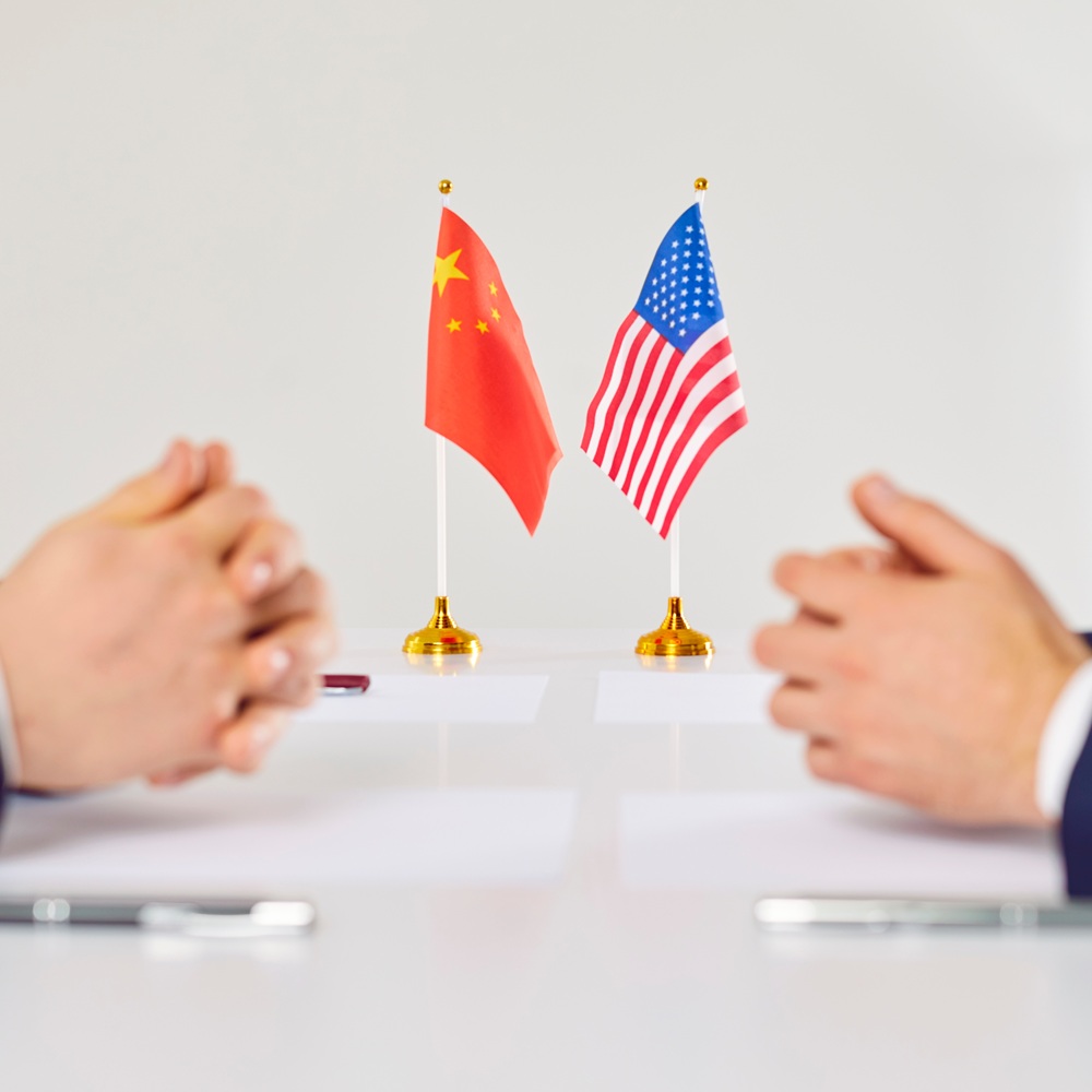 Flags of America and China atand on table during talks between diplomats and businessmen. American and Chinese representatives sit opposite each other to discuss relations between countries.