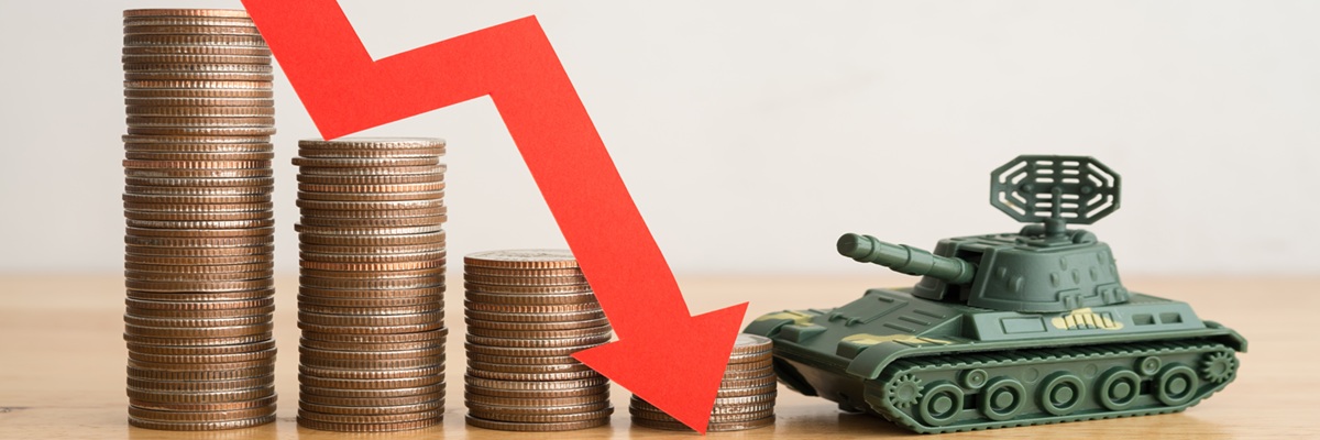Economic crisis impact of Russian invasion of Ukraine concept. Stacked coins, graph falling down and battle tank on wooden table background copy space. War effect to world economy.