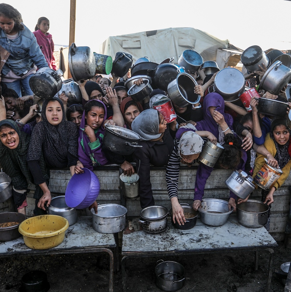 People gather to receive meals from the Rafah charitable kitchen (Tekka) as Palestinians face famine, in Khan Yunis, in the southern Gaza Strip, on January 2, 2025.