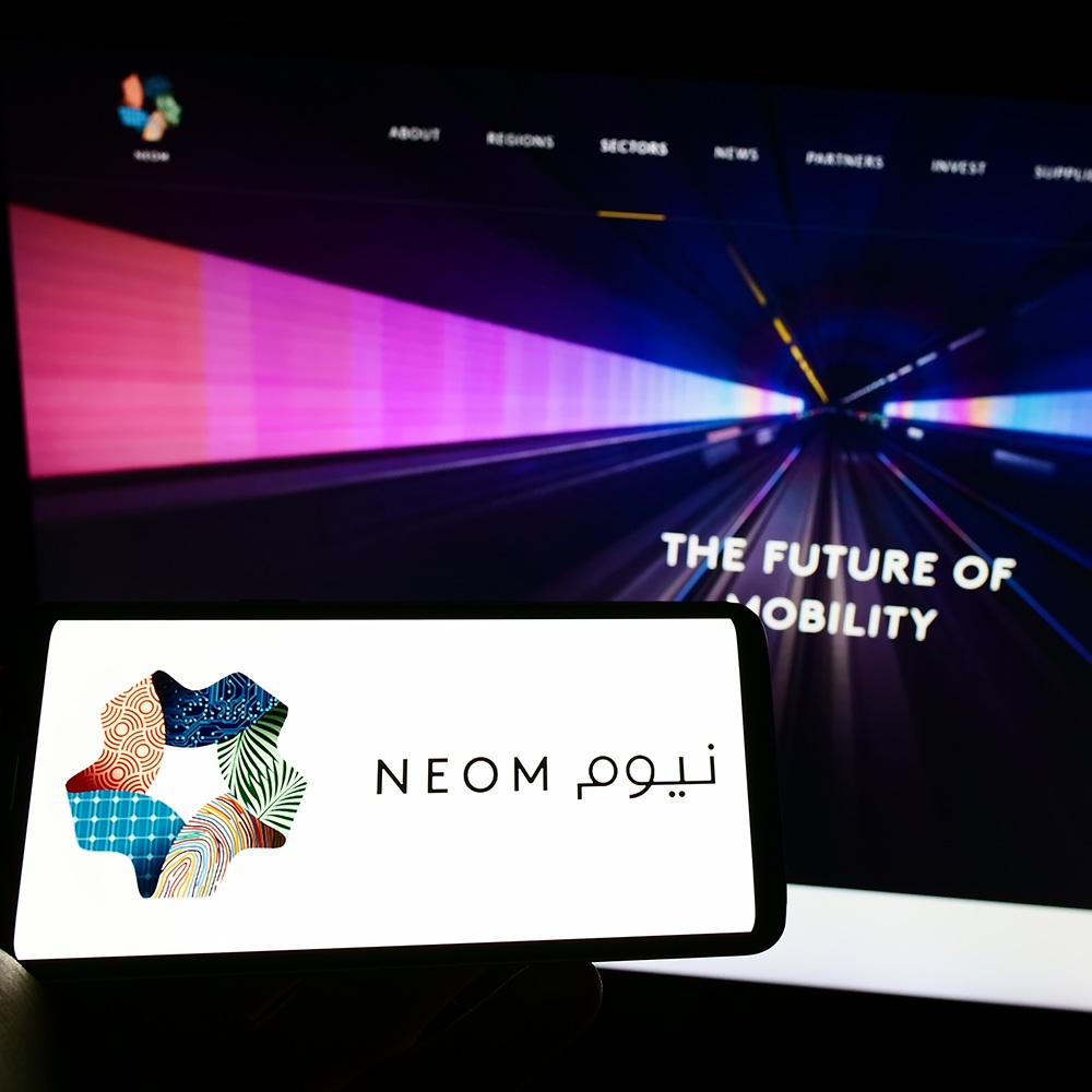 Stuttgart, Alemania - 10/01/2022: Persona con un teléfono móvil que muestra el logotipo de la promotora inmobiliaria saudí NEOM en la pantalla frente a una página web. Enfoque en la pantalla del teléfono. Foto sin modificar.