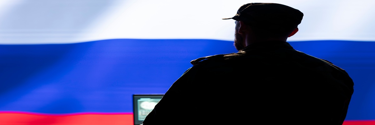 Ex KGB FSB secret police agent using mass propaganda technology tools on laptop to influence population minds. Russian spy silencing online opposition voices using notebook device