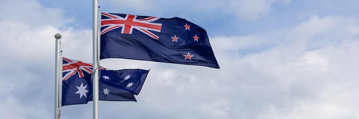 New Zealand and Australia national flags flying side by side against blue sky background